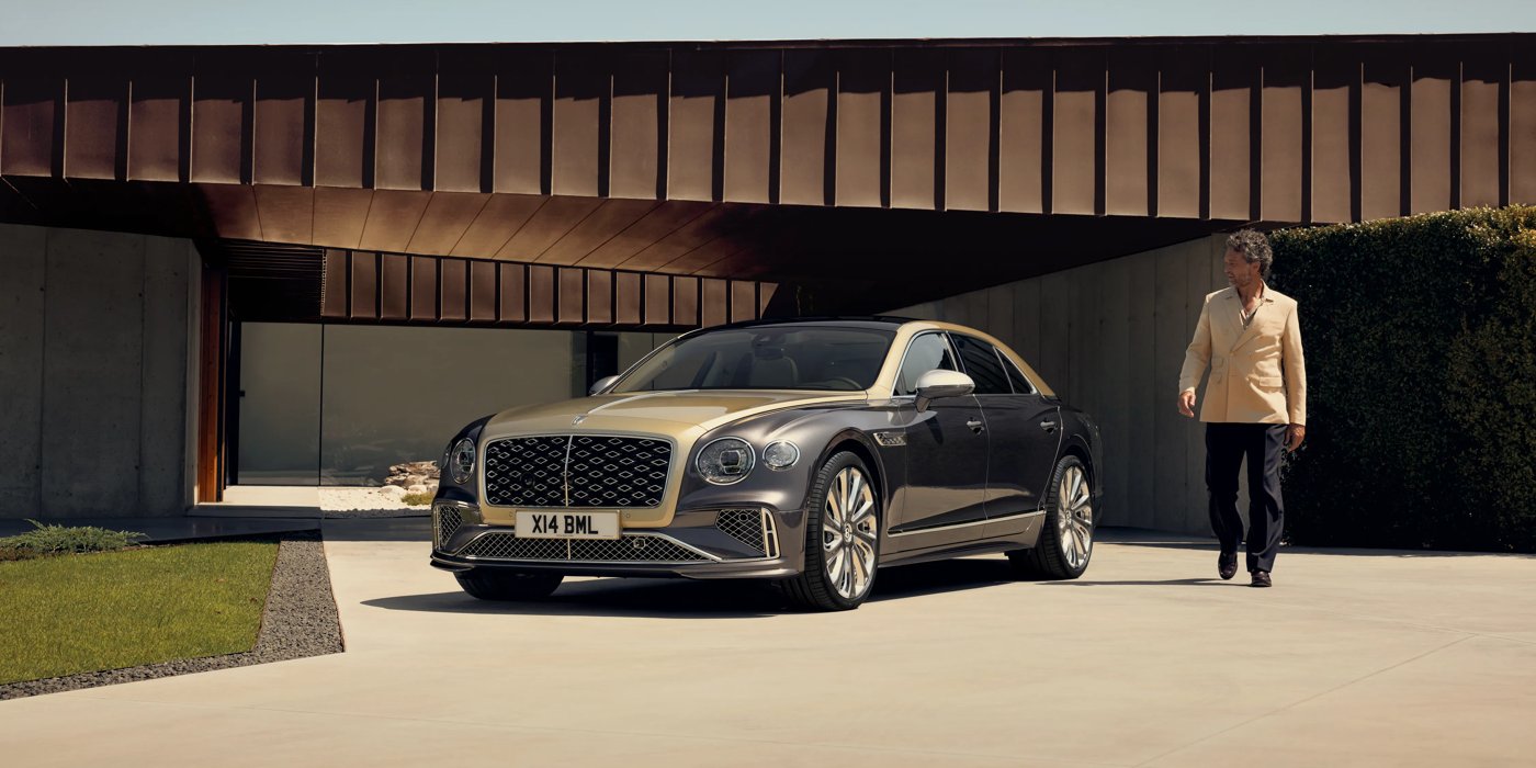 Bentley Bangkok Bentley New Flying Spur Mulliner V8 hybrid sedan front three quarters in Rose Gold over Magnetic paint, parked near modern home