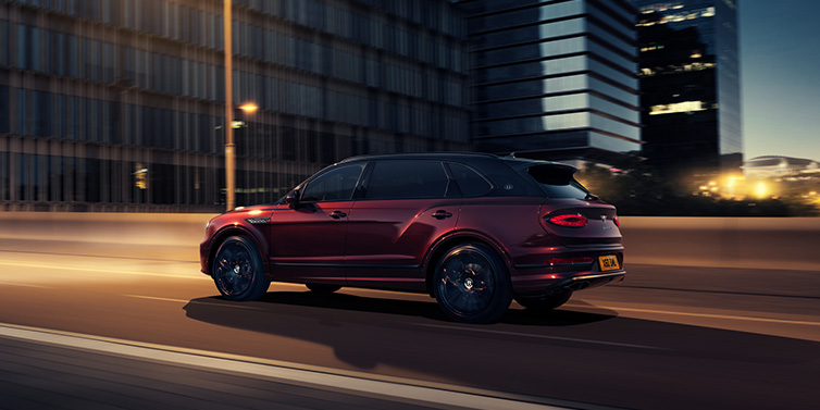 Bentley Bangkok Bentley Bentayga Extended Wheelbase Mulliner SUV in Cricket Ball red paint driving dynamically in city at night