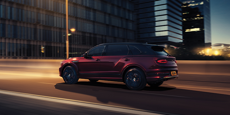 Bentley Bangkok Bentley Bentayga Extended Wheelbase Mulliner SUV in Cricket Ball red paint driving dynamically in city at night