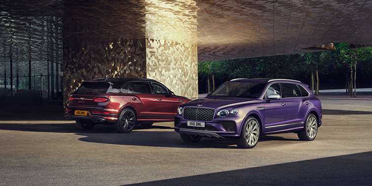 Bentley Bangkok A duo of Bentley Bentayga Extended Wheelbase Mulliner SUVs parked in a city environment, with Tanzanite Purple and Cricket Ball red exterior paint