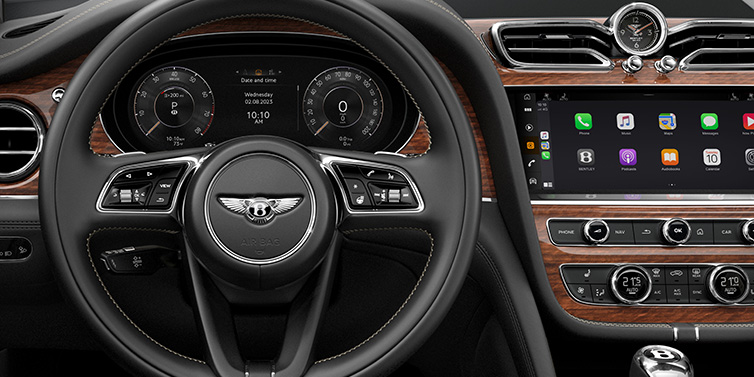 Bentley Bangkok Bentley Bentayga SUV front interior detail of steering wheel and driver screens surrounded by Beluga black hide and Crown Cut Walnut veneer